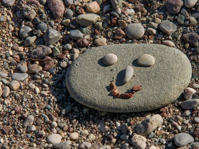 Gesicht aus Steinen am Kiesstrand